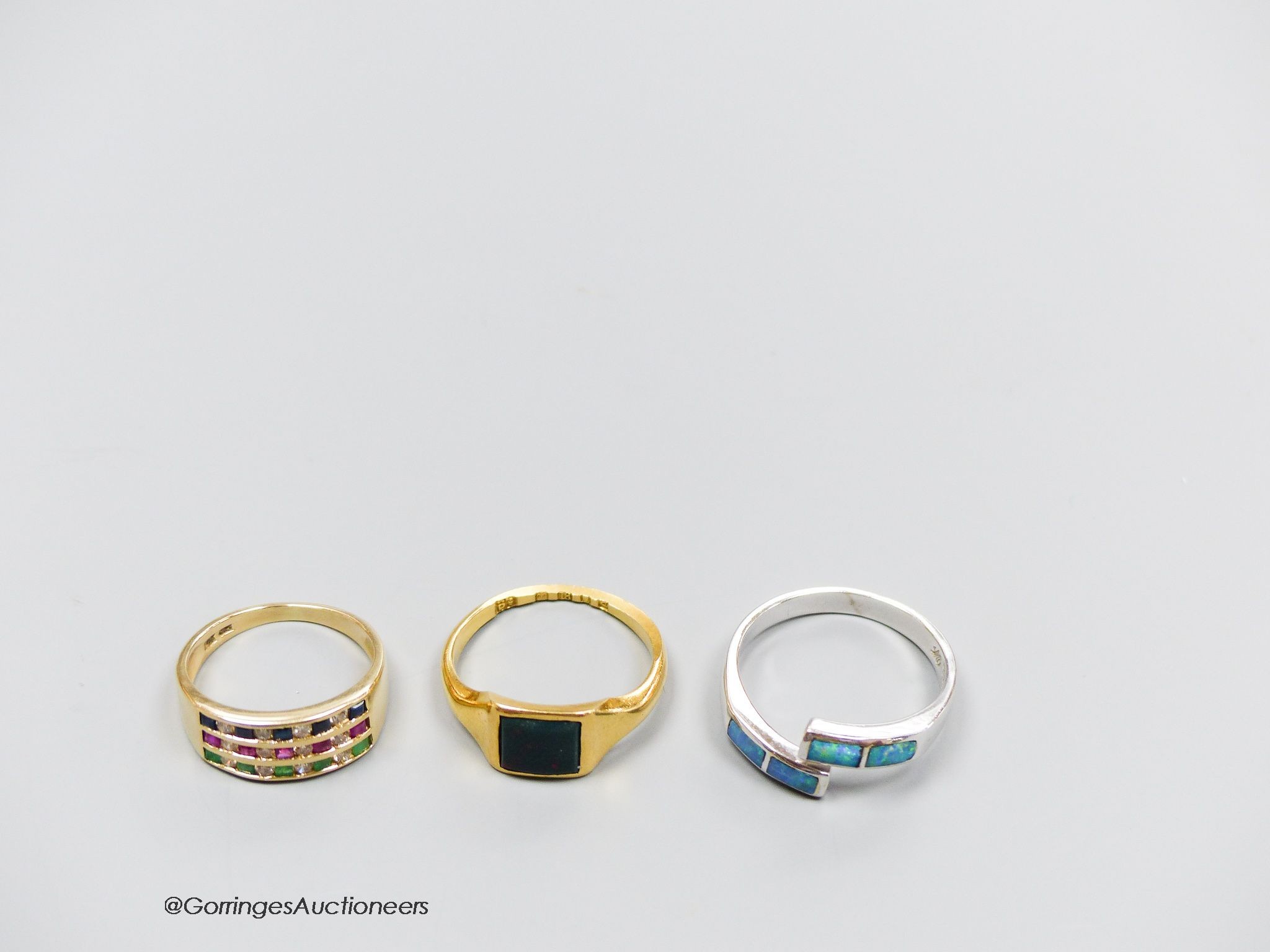 An 18ct white gold and opal ring, size Q, gross 4g, an 18ct gold and bloodstone ring, size O, gross 3g, and a 14k gold, sapphire, emerald, ruby and diamond ring, size L, gross 3g.